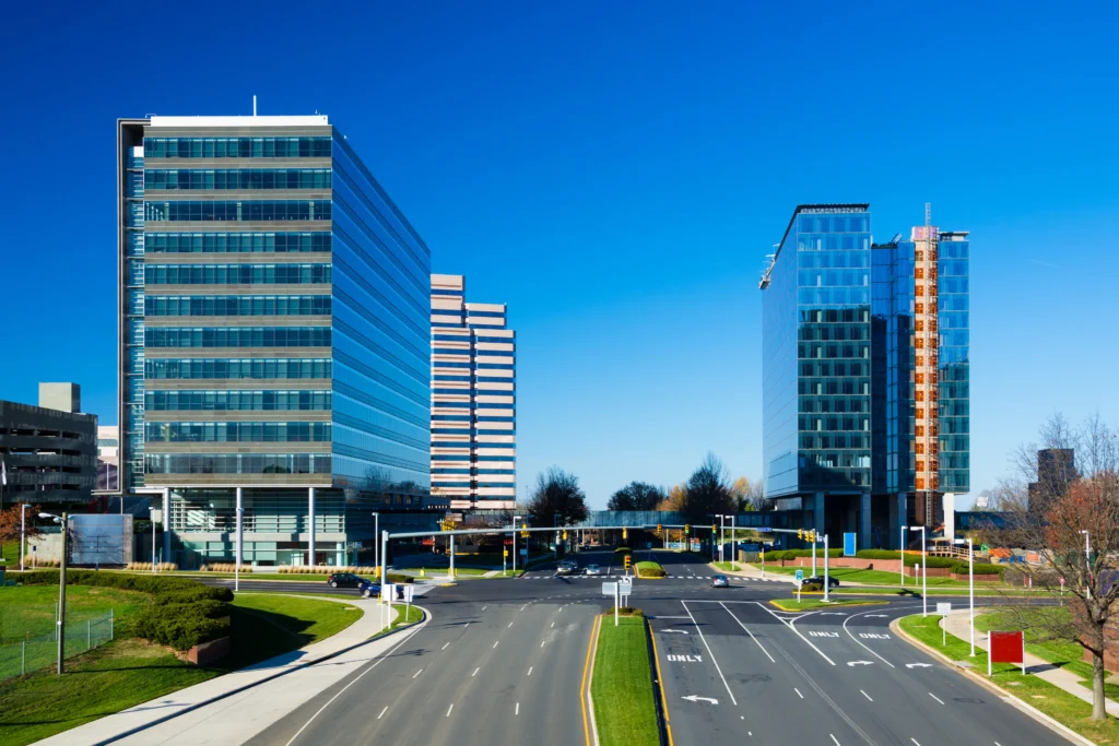 Modern office buildings and wide boulevard in McLean, VA, showcasing the city's upscale business district under a clear blue sky.